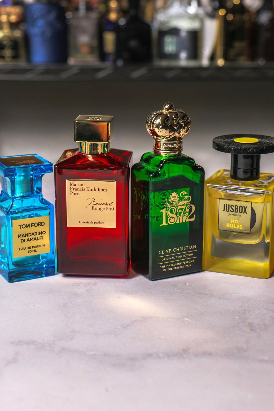 Perfumes nicho y de diseñador en fila sobre piedra clara