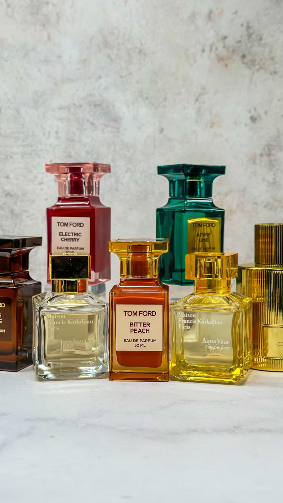 Frascos de Tom Ford, Chanel, Dior y Kilian sobre piedra clara